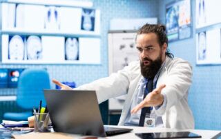 Doctor explaining medical concepts on a laptop during a virtual consultation, guiding how to find BlueCross BlueShield doctors for pain management services.