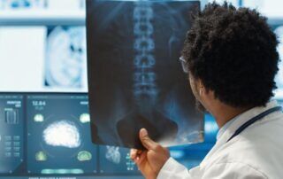 Doctor reviewing spinal X-ray while discussing BlueCross BlueShield coverage for pain management treatments